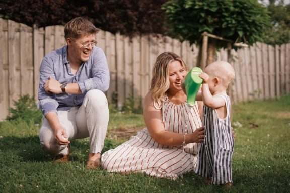 Eine Familie mit einem kleinen Kind im Garten, während sie gemeinsam spielen.